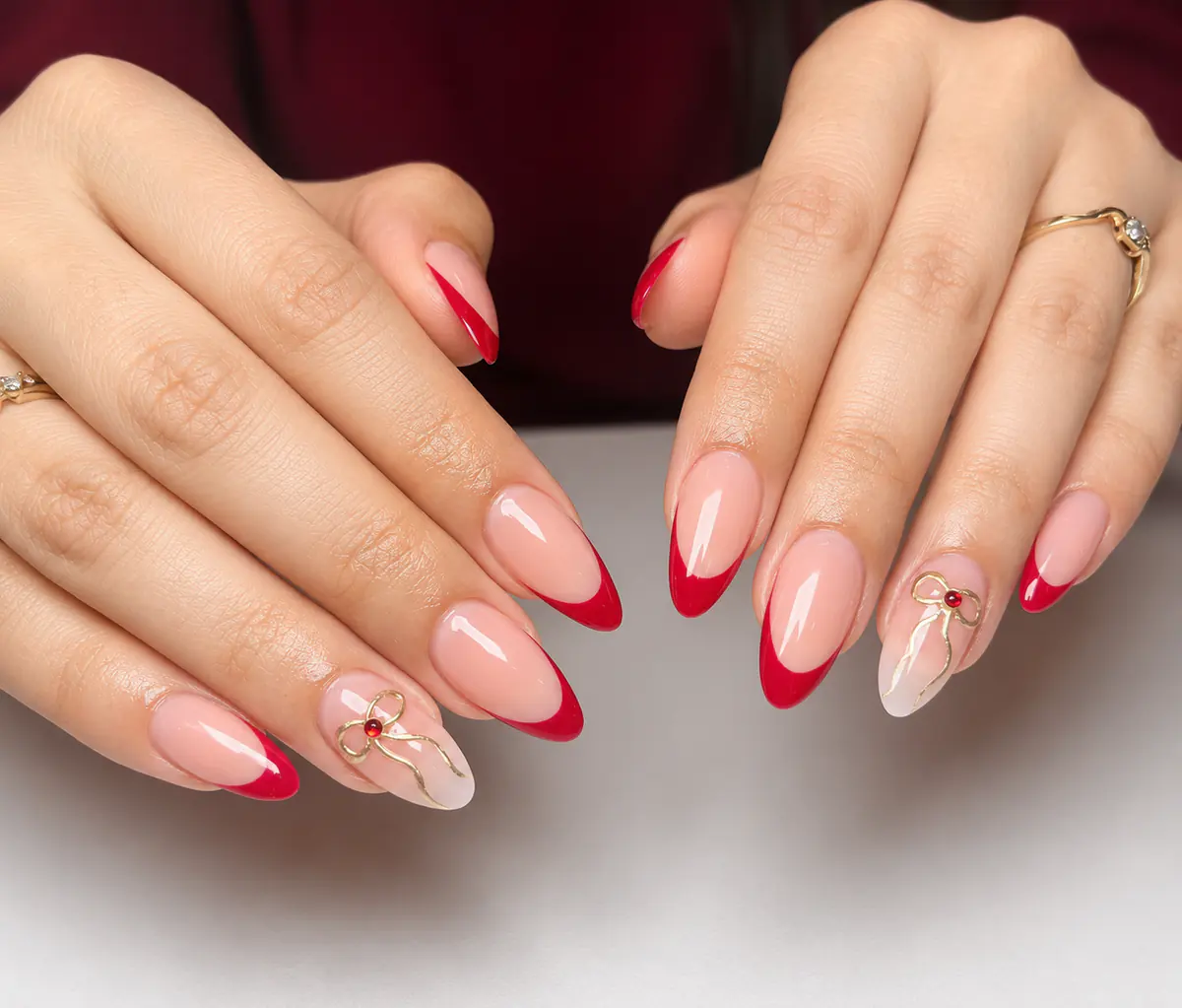 Red French manicure with delicate gold bows
